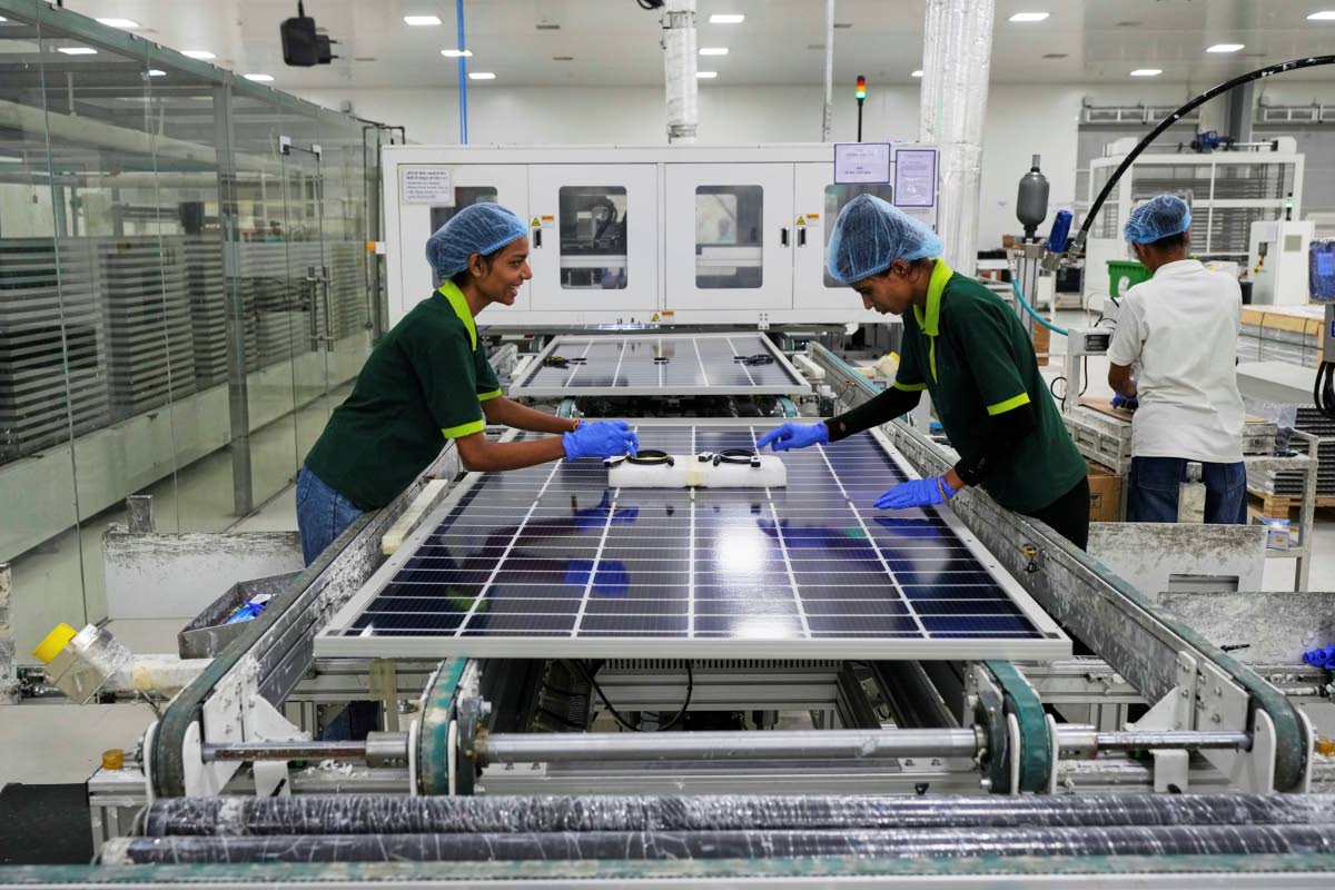 Workers put switches and connectors after they come out of automated framing at a ReNew solar panel manufacturing plant on the outskirts of Jaipur, India.