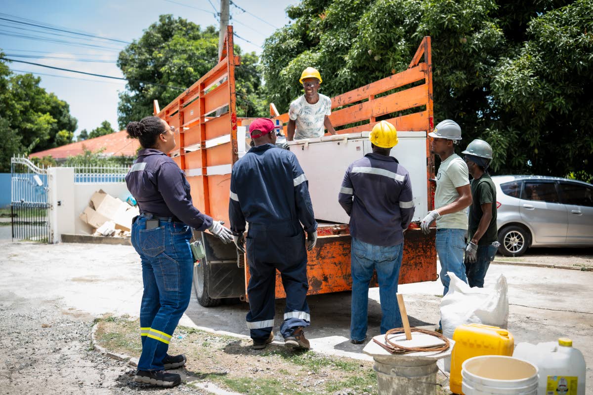 JPS Rockfort and Hunts Bay power station plant engineer, Timara Jackson (left), looks on as the moving team comprising (from second left) JPS instrument technician Colin Stone; power station maintenance man Arthur Chambers; Jeffrey Quarrie & Associates dri