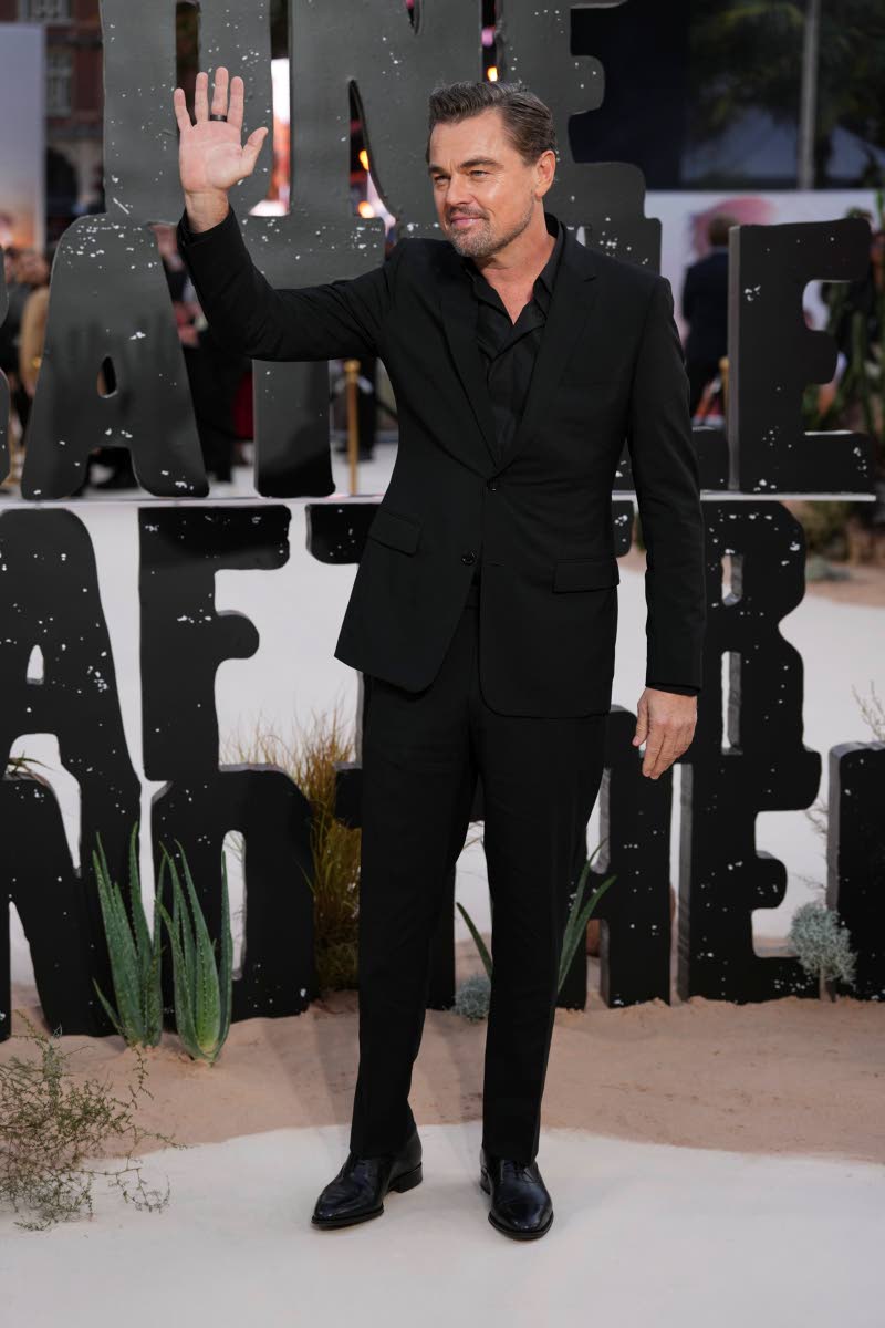 Leonardo DiCaprio dons an open-buttoned black shirt and an all-black suit.