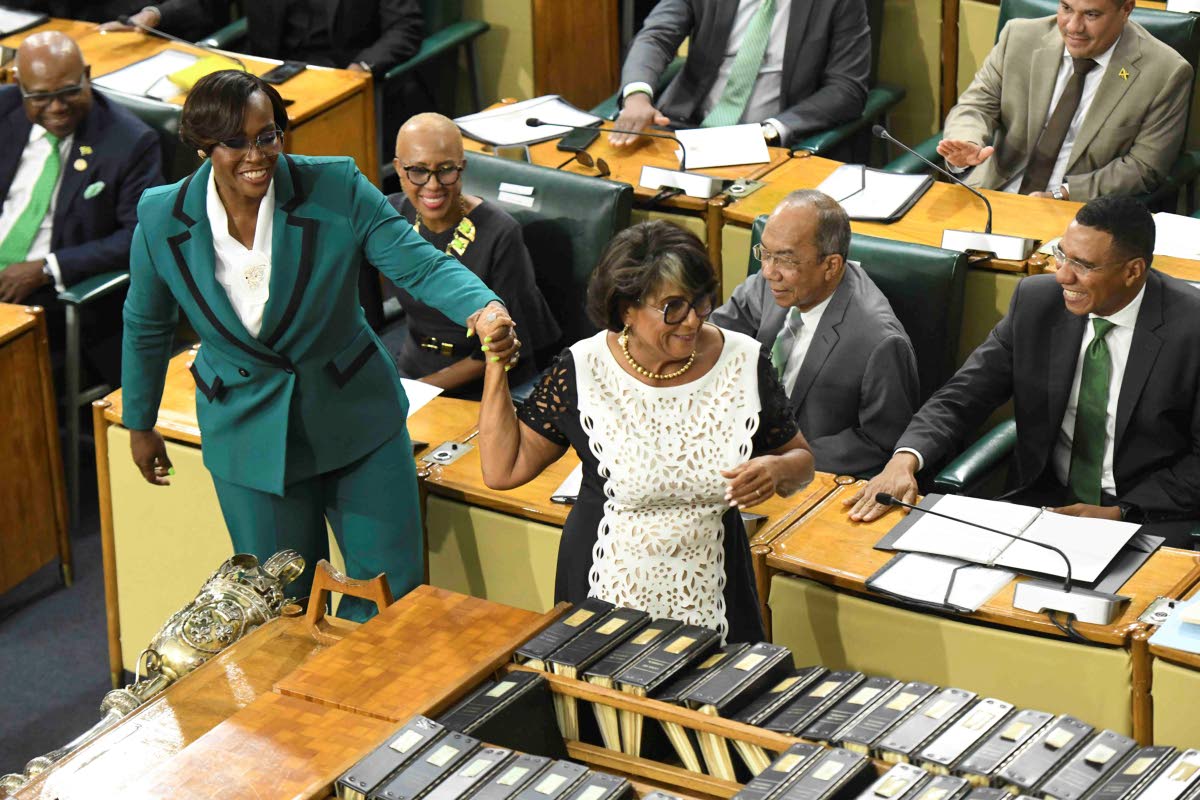 Newly elected House Speaker Juliet Holness (left) feigns reluctance as Former House Speaker Marisa Dalrymple-Philibert ‘drags’ her to the chair to take the oath of office during the swearing-in ceremony for members of the Upper and Lower Houses of Parl