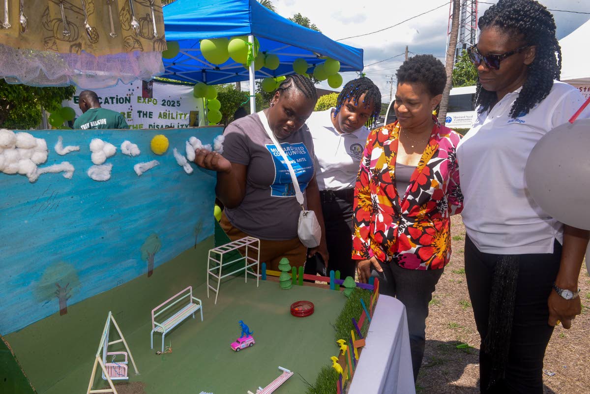 Special needs coordinator at the Ministry of Education, Skills, Youth and Information, Nicolette Thompson (second right), looks on as caregiver at Widow’s Mite, Shanice Spencer (left), highlights artwork created from recycled waste material during the Mu