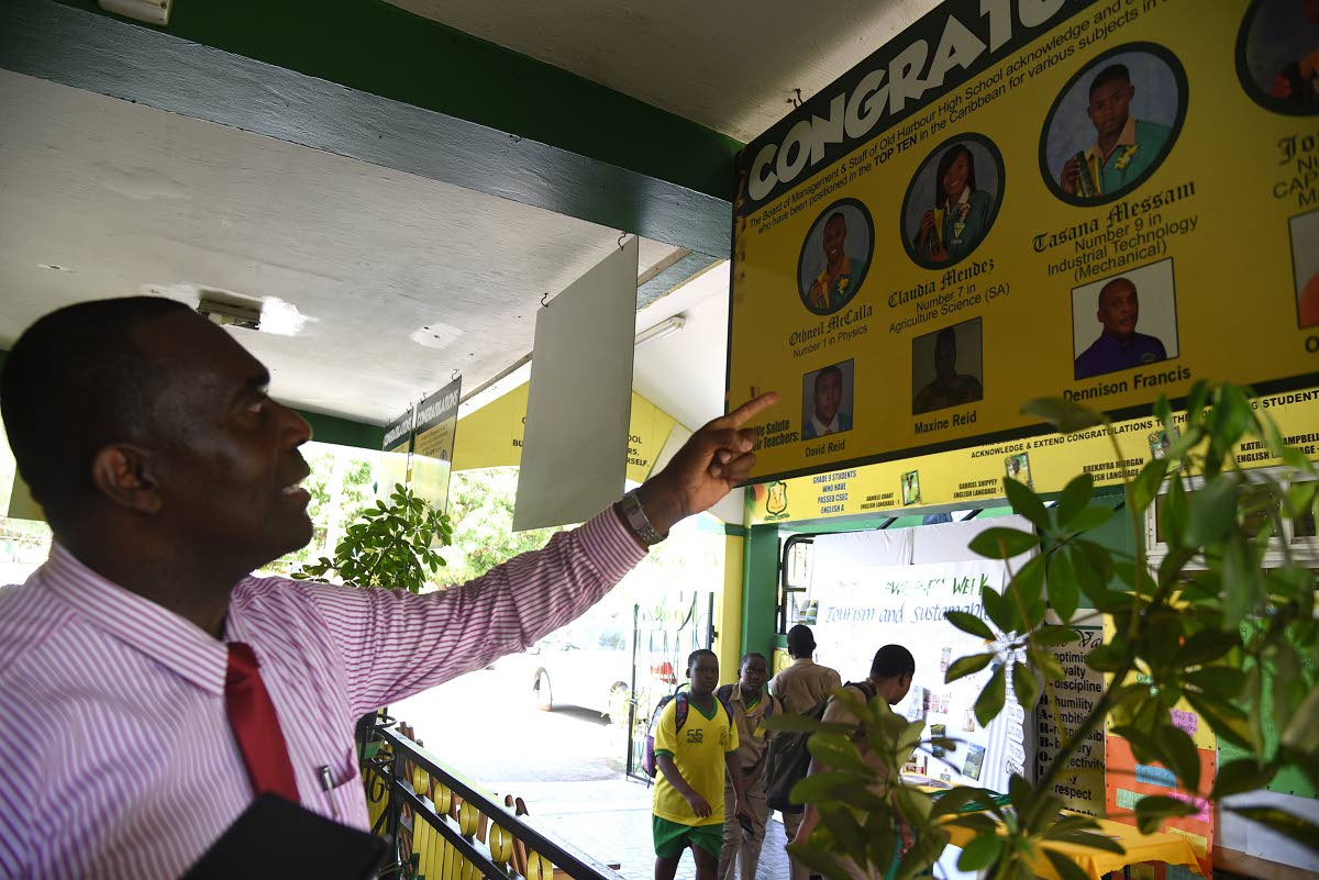 Lynton Weir, principal of Old Harbour High School, shows off the display board highlighting honour students at the school. 