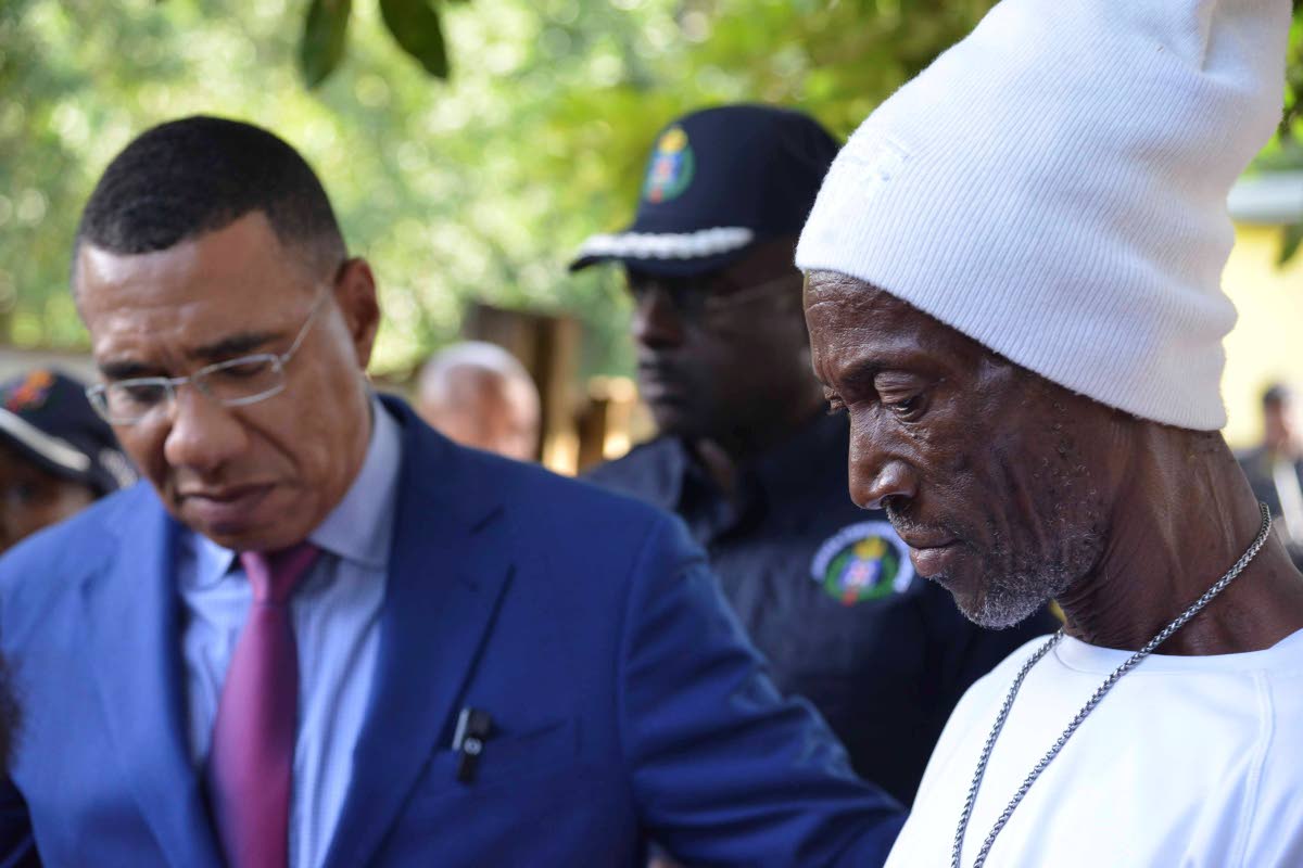 Prime Minister Dr Andrew Holness listens keenly as Everton Walters (right), father of Joshane Walters, reflects on the type of person his son was. Joshane was among nine persons shot by gunmen on Sunday. He subsequently died, along with four others.