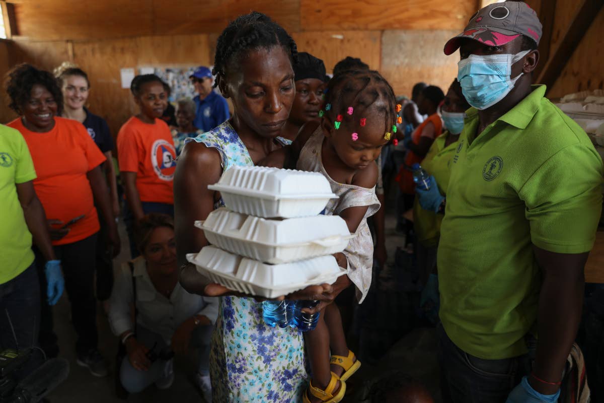 A woman carrying a child walks away with food from the World Food Program (WFP) at the Jean Marie Vincent High School which has been turned into a shelter for families displaced by gang violence in the Tabarre neighbourhood of Port-au-Prince, Haiti.