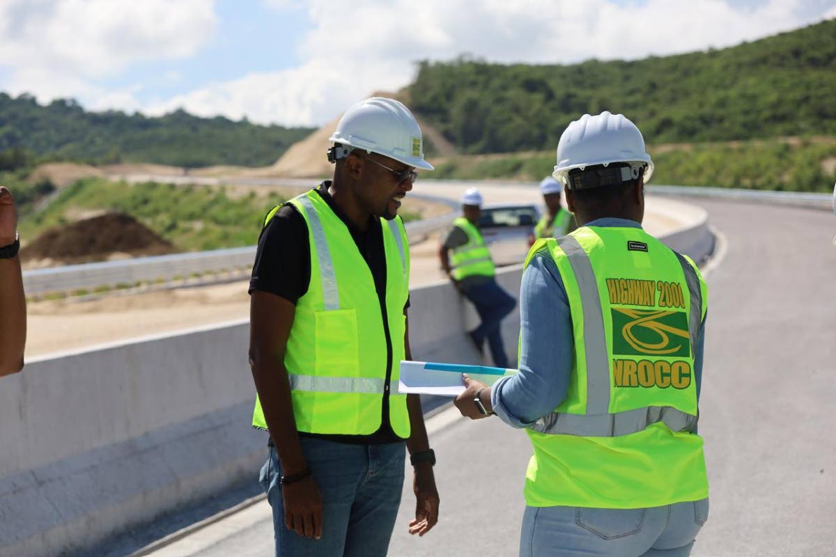 Robert Morgan (left), minister without portfolio in the Ministry of Economic, Growth and Job Creation with responsibility for works, examines documents related to the Montego Bay Perimeter Road, now under construction, during a tour of the construction sit
