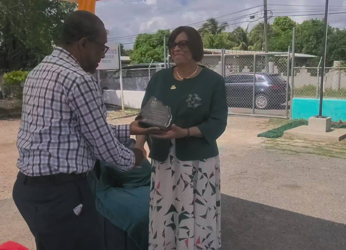 Principal Dr Una Eugenie Harrison, of Harrison’s Preparatory, receives her plaque from chairman of the school John Hutchinson during the institution’s Heritage Week celebration last Wednesday.
