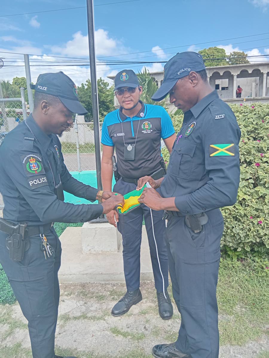 Police personnel prepare the Jamaican flag to be raised for the first time at the Harrison’s Preparatory School in St Catherine.