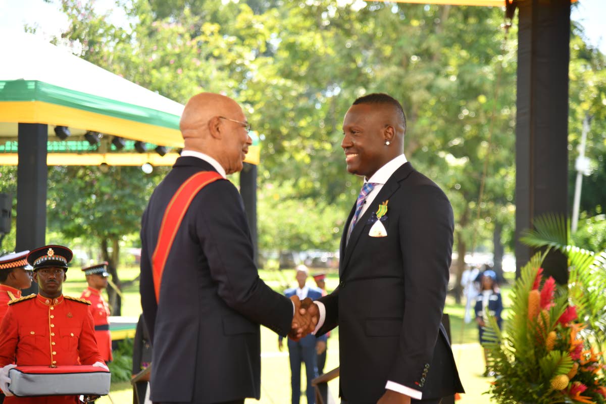 Former West Indies captain Rovman Powell shakes the hand of Governor General Sir Patrick Allen after getting pinned at the Ceremony of Investiture and Presentation of National Honours and Awards on the lawns of King’s House yesterday.
