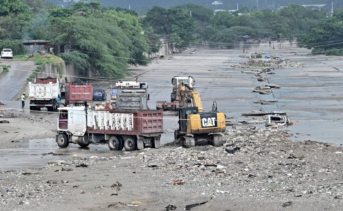 Heavy equipment and trucks are seen at Sandy Gully clearing debris and garbage ahead of Tropical Storm Melissa.