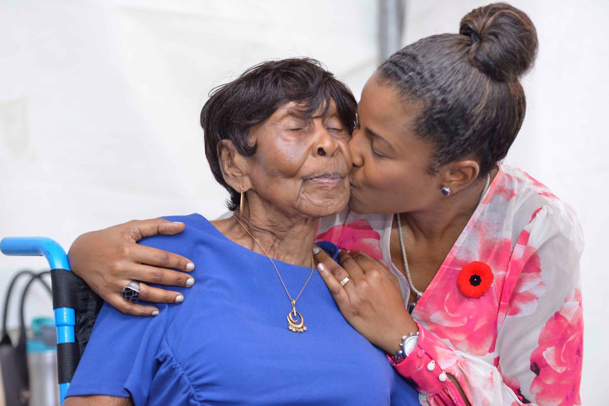 Michelle Williams gives her mother, Elsa Louise Atkinson, an affectionate kiss on the cheek. Atkinson says she is blessed to have received the honour for her six decades of service in pharmacy.