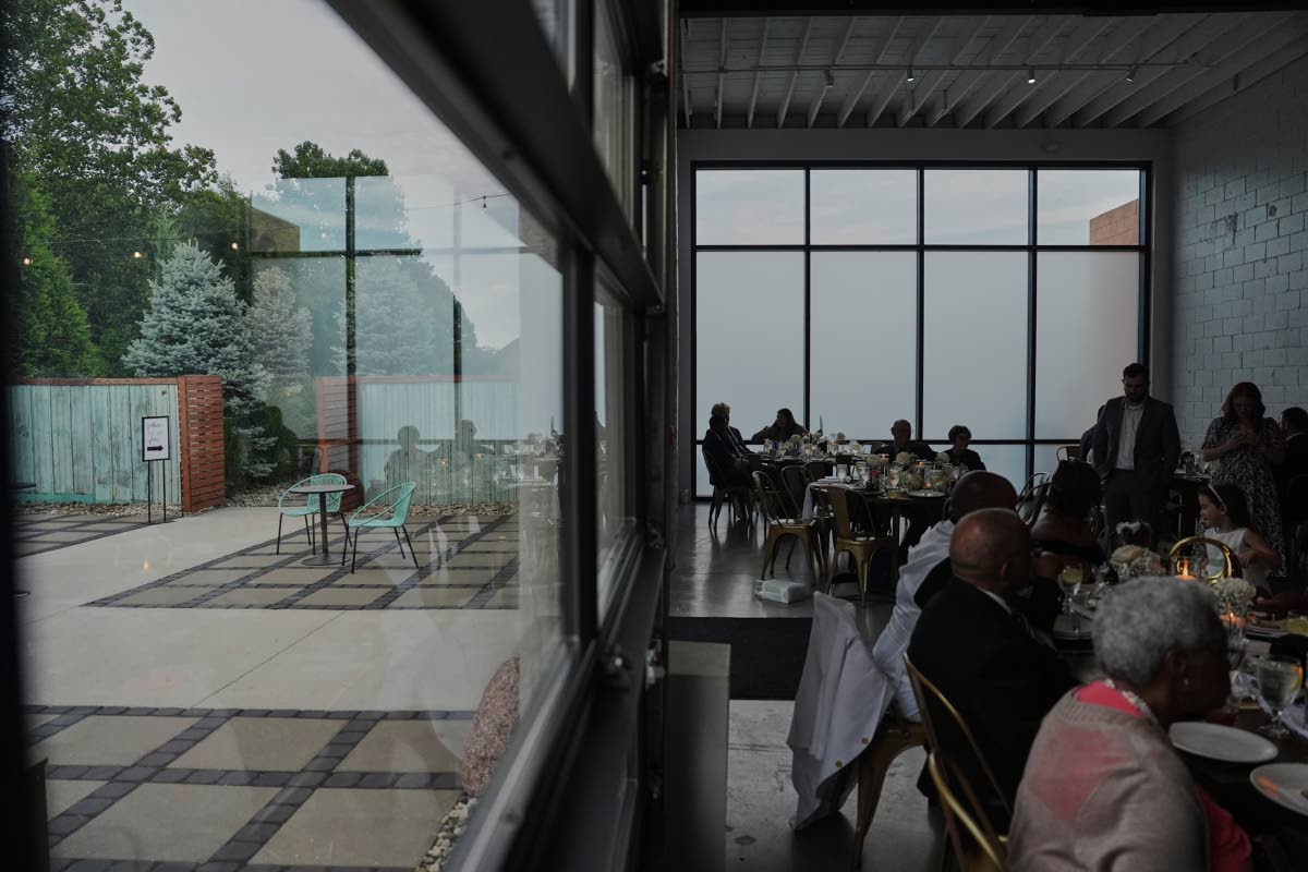 At BOTTOM: Guests sit inside during cocktail hour as empty chairs sit outside during a wedding on August 23, 2025 in Newtown, Ohio.