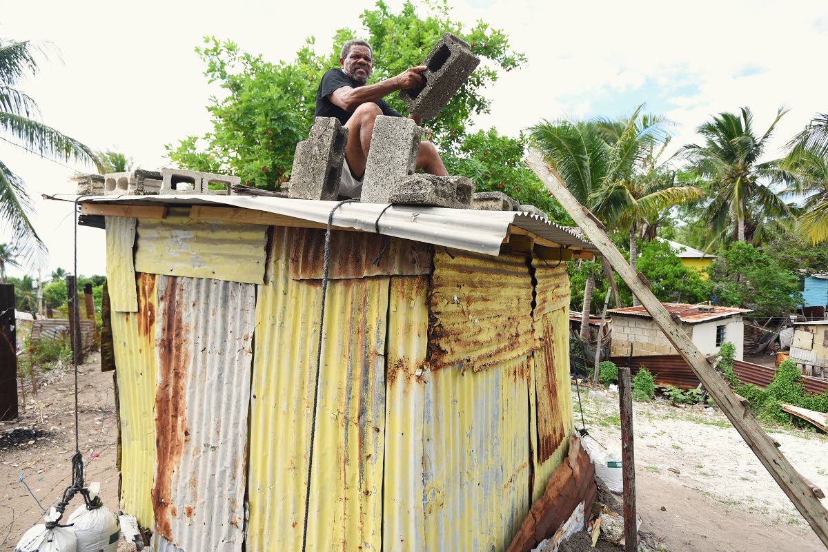 Robert Gordon uses building blocks to secure a section of his roof in anticipation of the arrival of Hurricane Melissa.