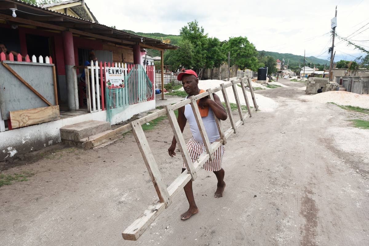Cleon Banton from Compound in Allligator Pond, Manchester, carries a ladder home to gain access to his roof to batten down for Hurricane Melissa last Friday.