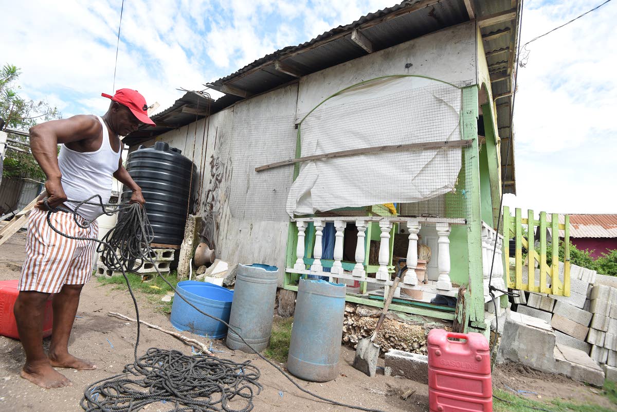 Cleon Banton prepares rope to tie down the roof of his house in Compound, Alligator Pond, Manchester, last Friday as Hurricane Melissa approaches.