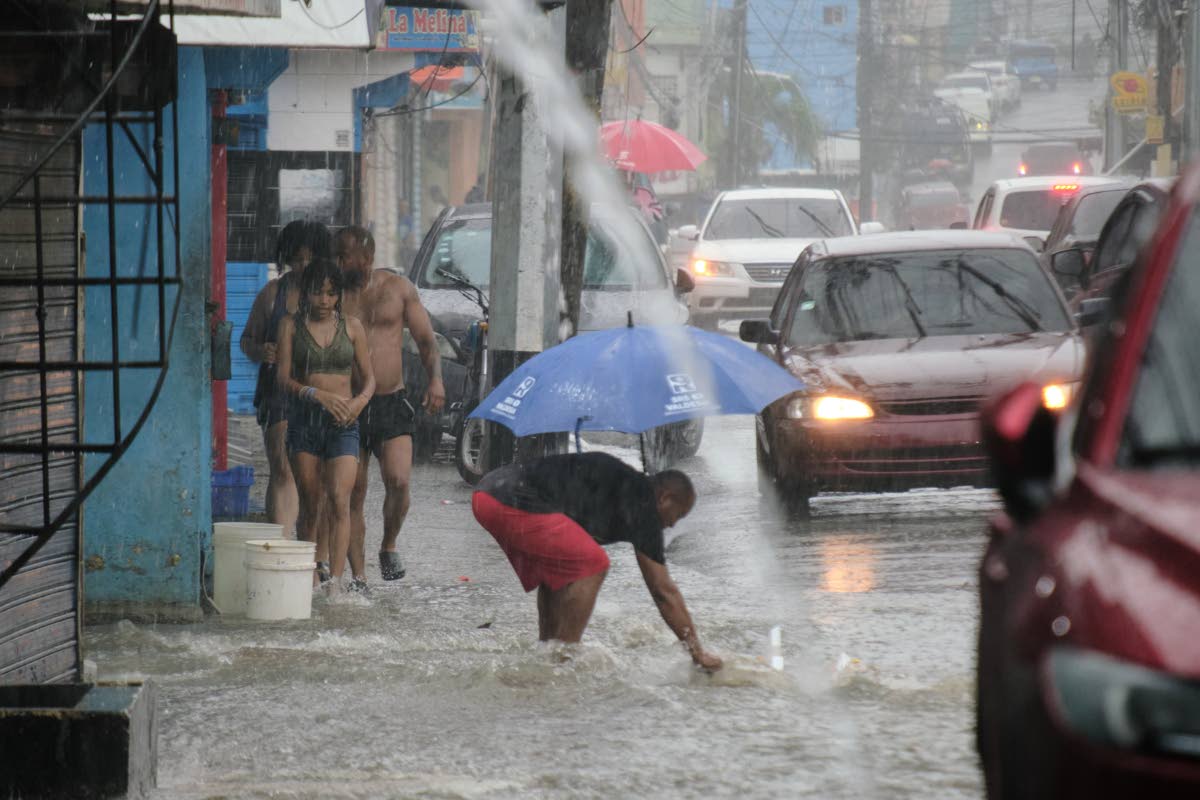 People walk in a street flooded by rains caused by Tropical Storm Melissa in Santo Domingo, Dominican Republic.