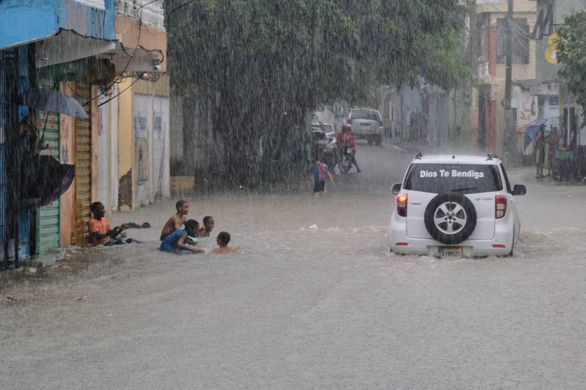 Children playing in a street flooded by rains caused by Tropical Storm Melissa in Santo Domingo, Dominican Republic.