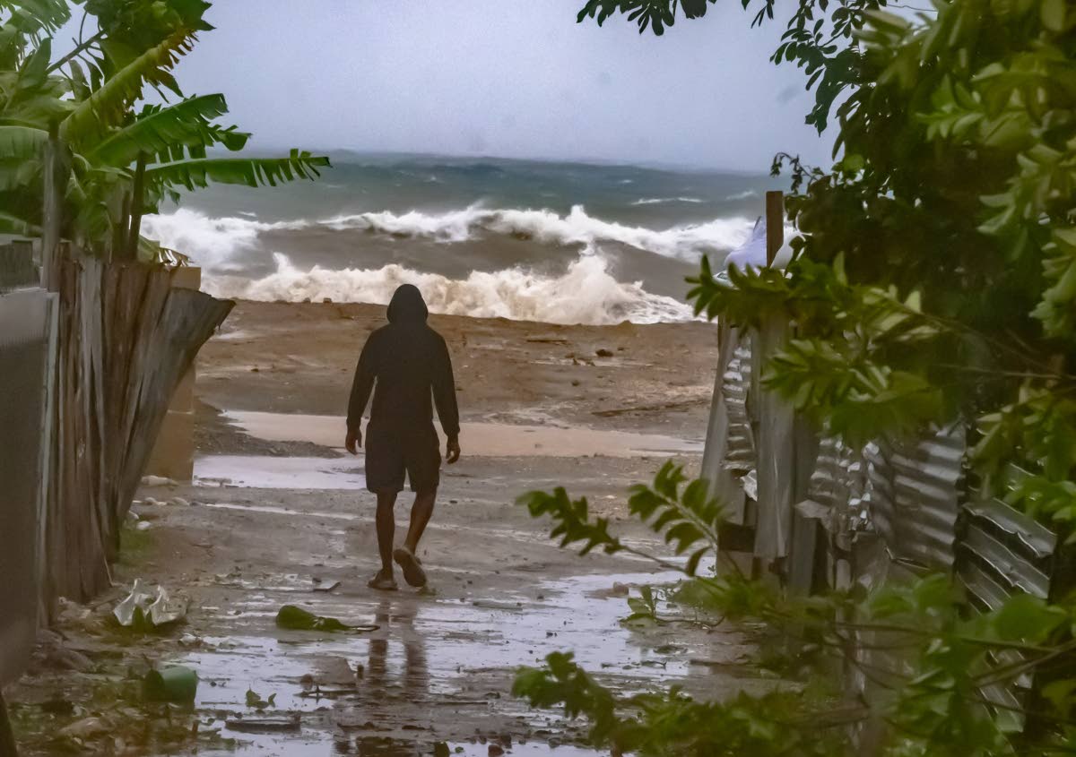 A man walks towards the shoreline at Seven Miles, Bull Bay, before the passage of Hurricane Melissa.