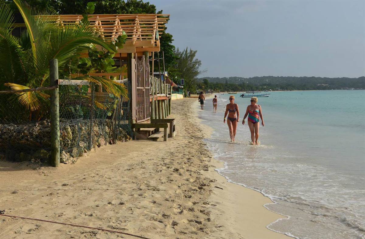 Tourists walk along a beach in Negril.