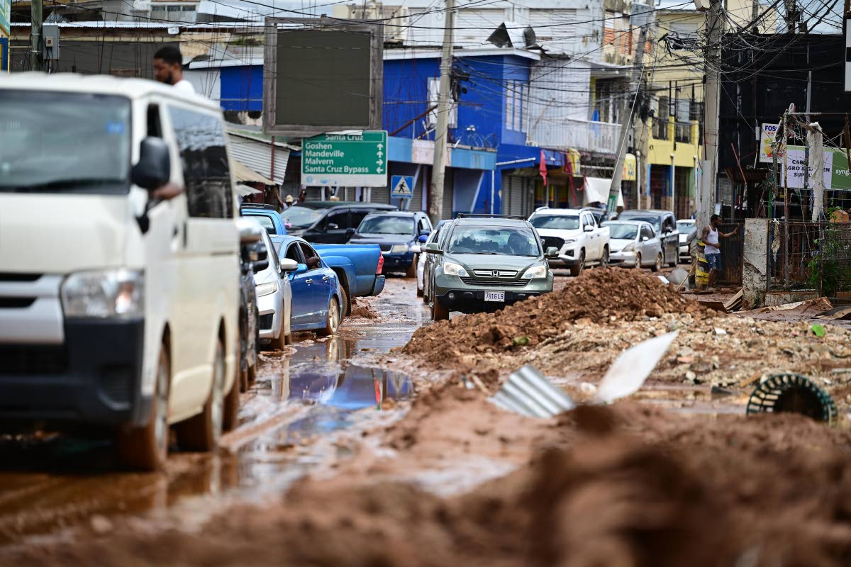 Motorists navigate the streets of Santa Cruz, which were filled with mud and debris left in the wake of Hurricane Melissa.