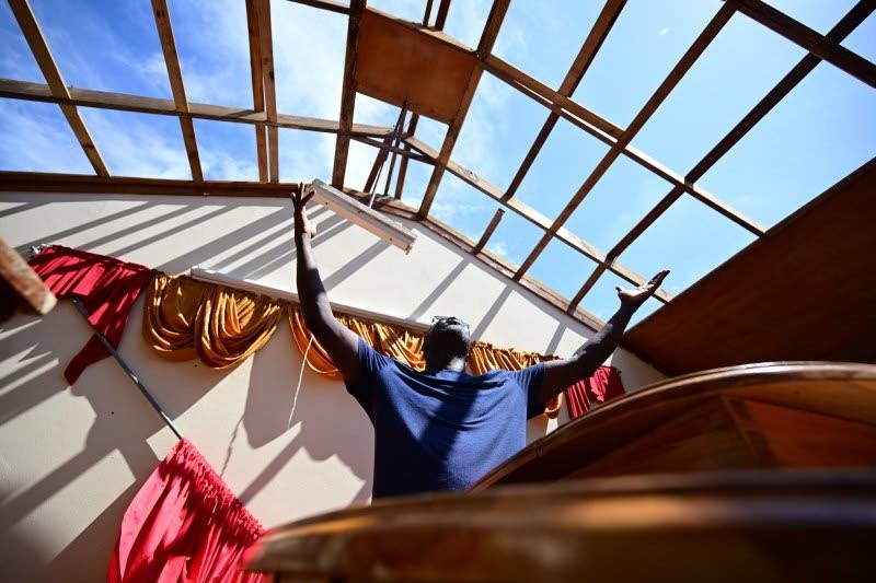  Gladstone Taylor/Multimedia Photo Editor 
Sherman Graham, pastor of Brucefield Gospel Chapel in Brucefield, St Elizabeth, in a moment of reverence at the pulpit of his roofless church on Thursday. The church is one of several across western Jamaica batter