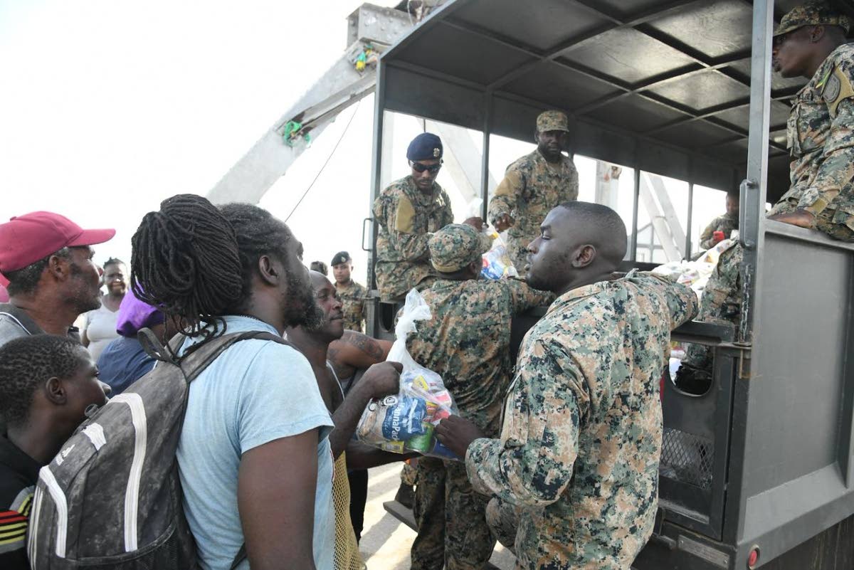 Members of the Jamaica Defence Force hand out care packages to residents of Crane Road in St Elizabeth. 