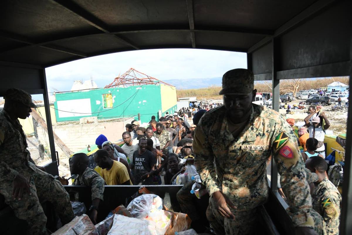 Members of the Jamaica Defence Force hand out care packages to residents of Crane Road in St Elizabeth. 