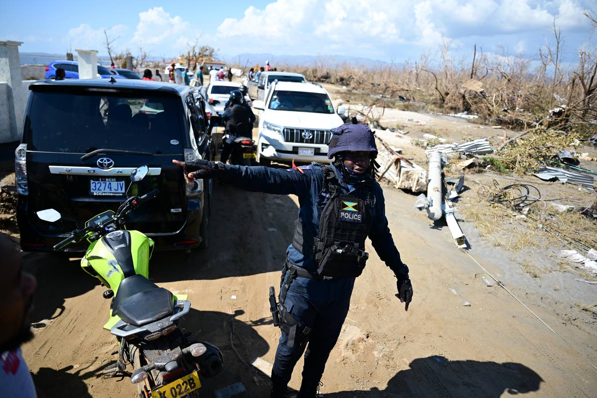 Members of the Jamaica Constabulary Force assist in traffic management at a section of Crane Road in Black River, St Elizabeth. The roadway was heavily covered in sand and proved difficult for motorists to navigate.
