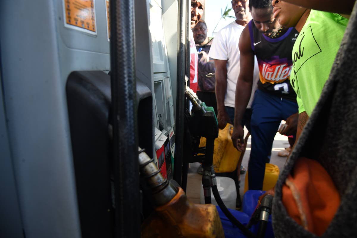 People in Savanna-la-Mar, Westmoreland, scramble to get gasoline for vehicles and generators at Yaadman and Total gas stations on Friday.