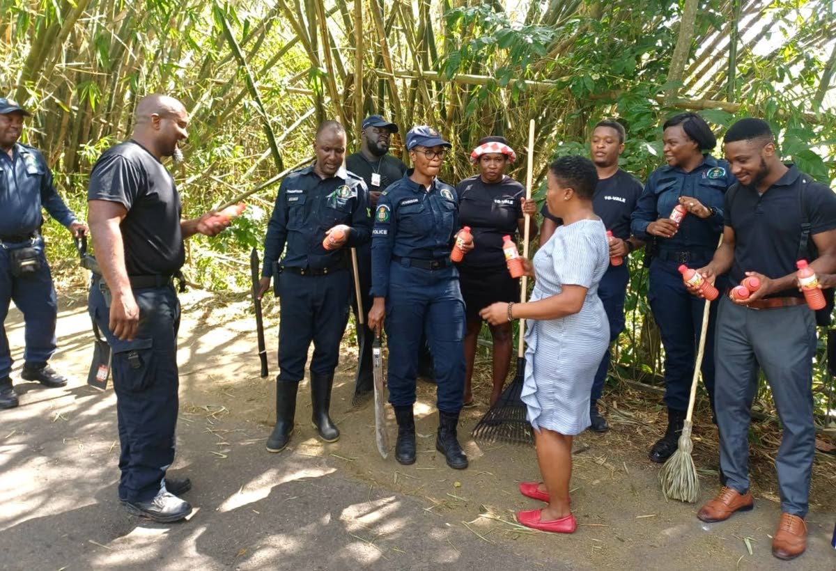 Principal of the Guanaboa Vale Primary School in St Catherine, Tracey-Ann Brown (centre), serves bottled drinks to officers of the Guanaboa Vale Police Station on November 3 during a workday to clear debris from the roadway, caused by Hurricane Melissa.