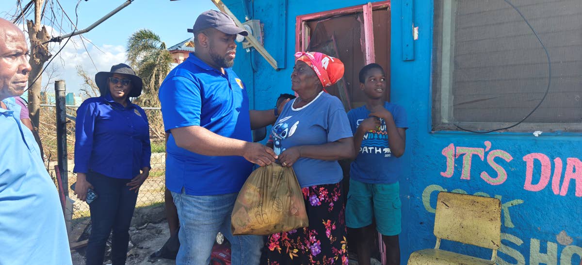 Lola Bent is thankful for her care package personally delivered to her by Donmayne Gyles, president/CEO, Andrews Memorial Hospital, during its outreach in the community on November 4. Malik, her neighbour, looks on. 