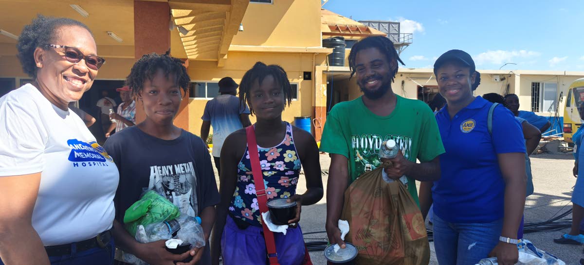 Flanked by AMH’s Charmaine Blythe (left), assistant laboratory manager, and Alanie Lewis (right), human resources director, are cousins, Sonia Davy, Jay Davy and Wilton Forbes, who received care packages during AMH’s outreach at Black River Hospital an