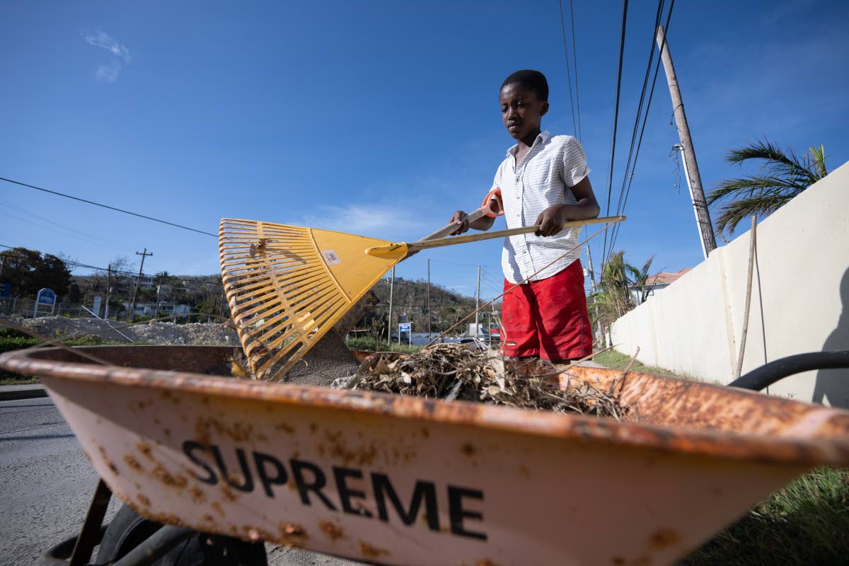 Twelve-year-old Stephen Green cleans up small pieces of debris from in front of his home, situated on Hopewell main road in Hanover.
