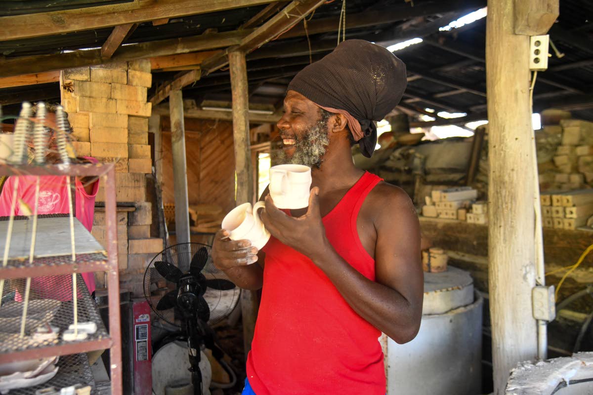 Ian Garvey, potter and studio assistant, shows off a few mugs for a corporate client before they are cleaned up, glazed and bisque-fired in the gas kiln.