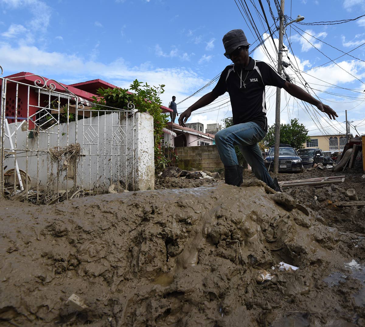 Nicolee Wynter, a resident of Westgreen, struggles to walk through knee-high mud nearly a week after the passage of Hurricane Melissa.