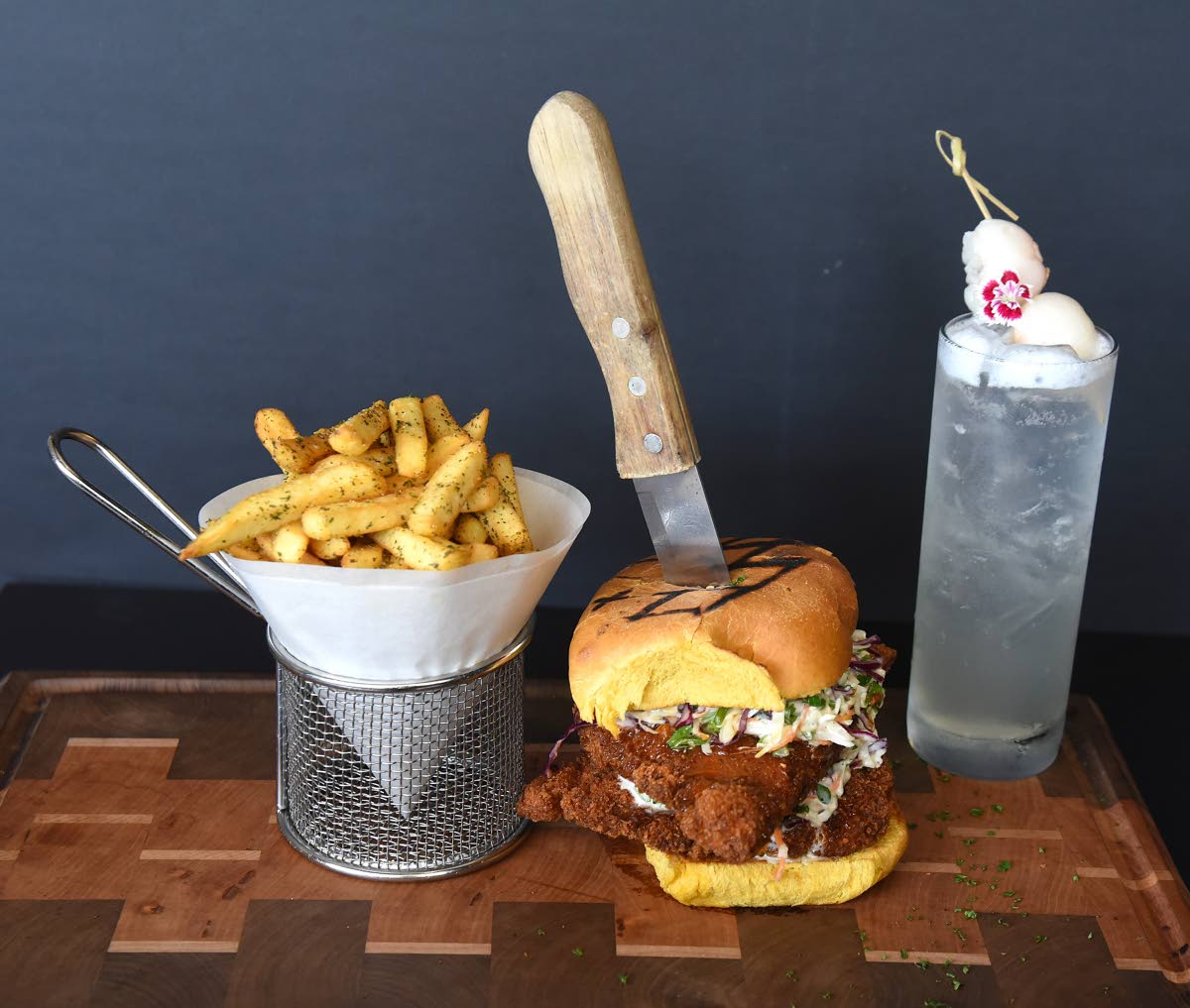 This stacked Park crispy chicken sandwich is served with a side of seasoned fries. Sharing the spotlight is the refreshing lychee spritz. 