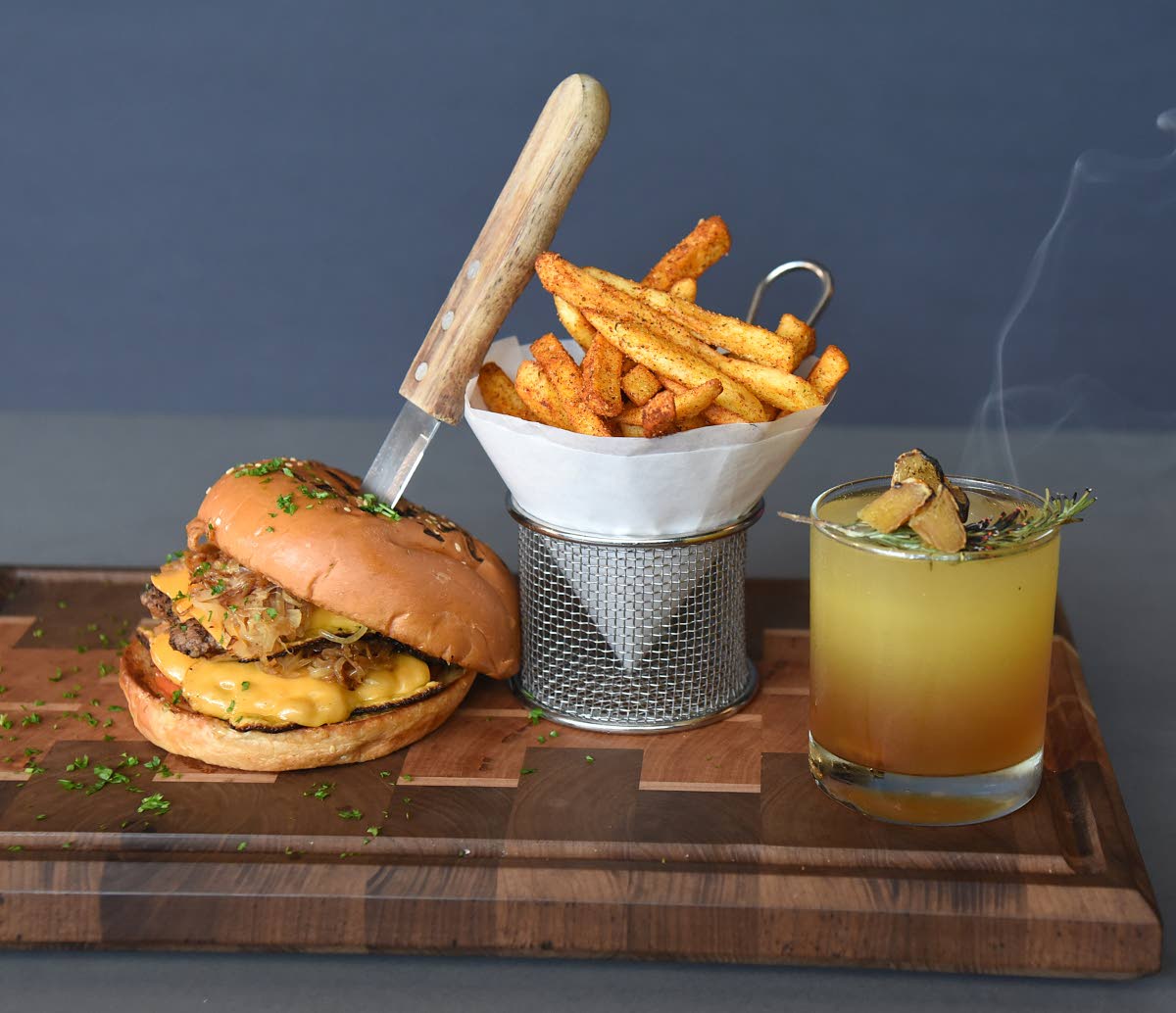 The featured storm breaker burger, served with fries, stood proudly in the good company of this smoky Amber elixir cocktail.