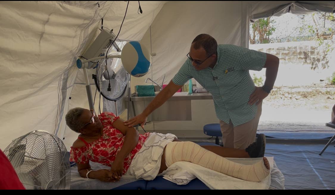 Dr Christopher Tufton speaks to a patient at the Falmouth field hospital who suffered a broken leg in an accident.