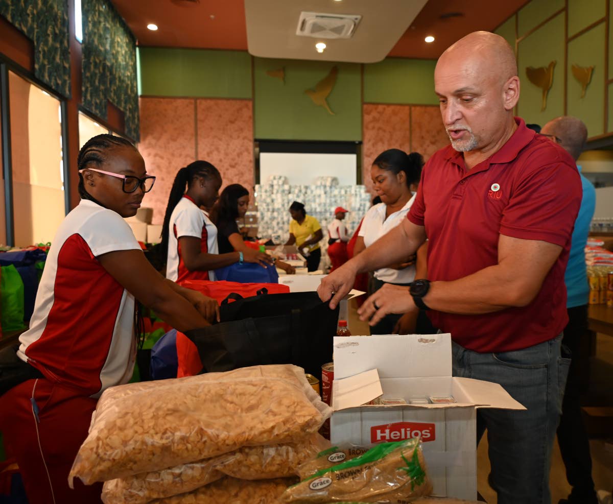 Rusheda McKenzie (left) of RIU Montego Bay’s entertainment department and Frank Sondern, RIU’s regional operations director for Jamaica (right), prepare care packages for staff on Wednesday.