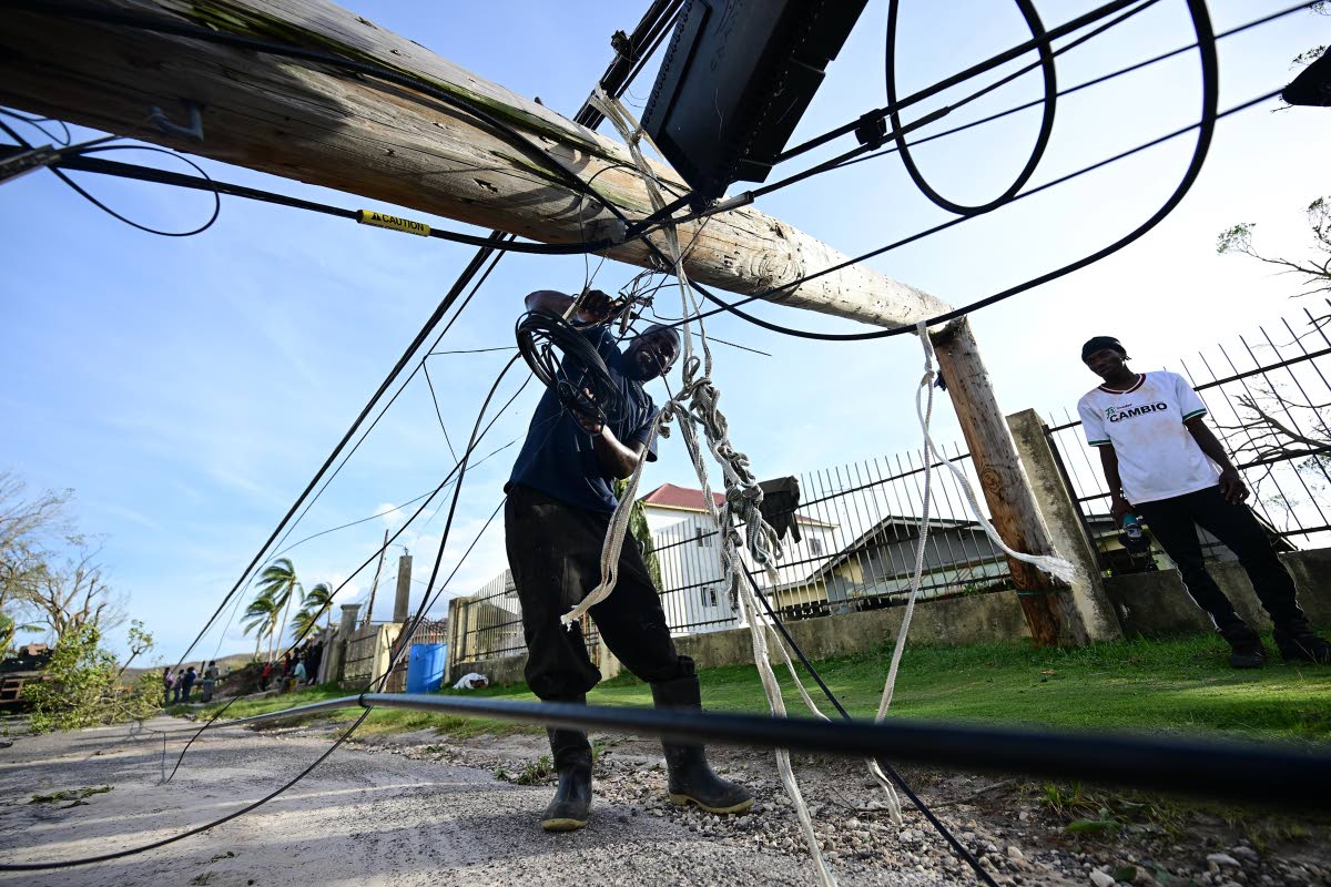 A man clears a roadway in Lacovia, St Elizabeth, after downed power poles blocked it during Hurricane Melissa.