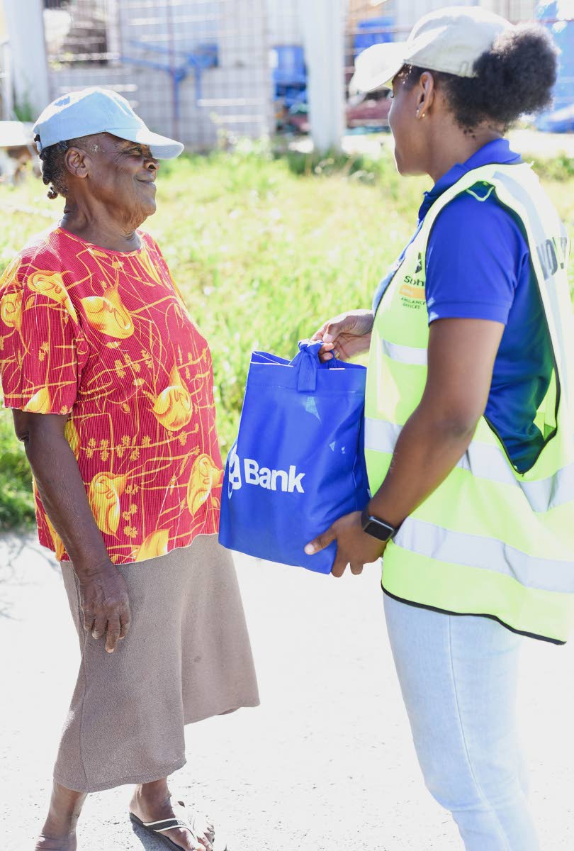 Piilar Ellington (right), a JN Group volunteer, hands a hurricane relief package to Beverly Smith of south Trelawny.
