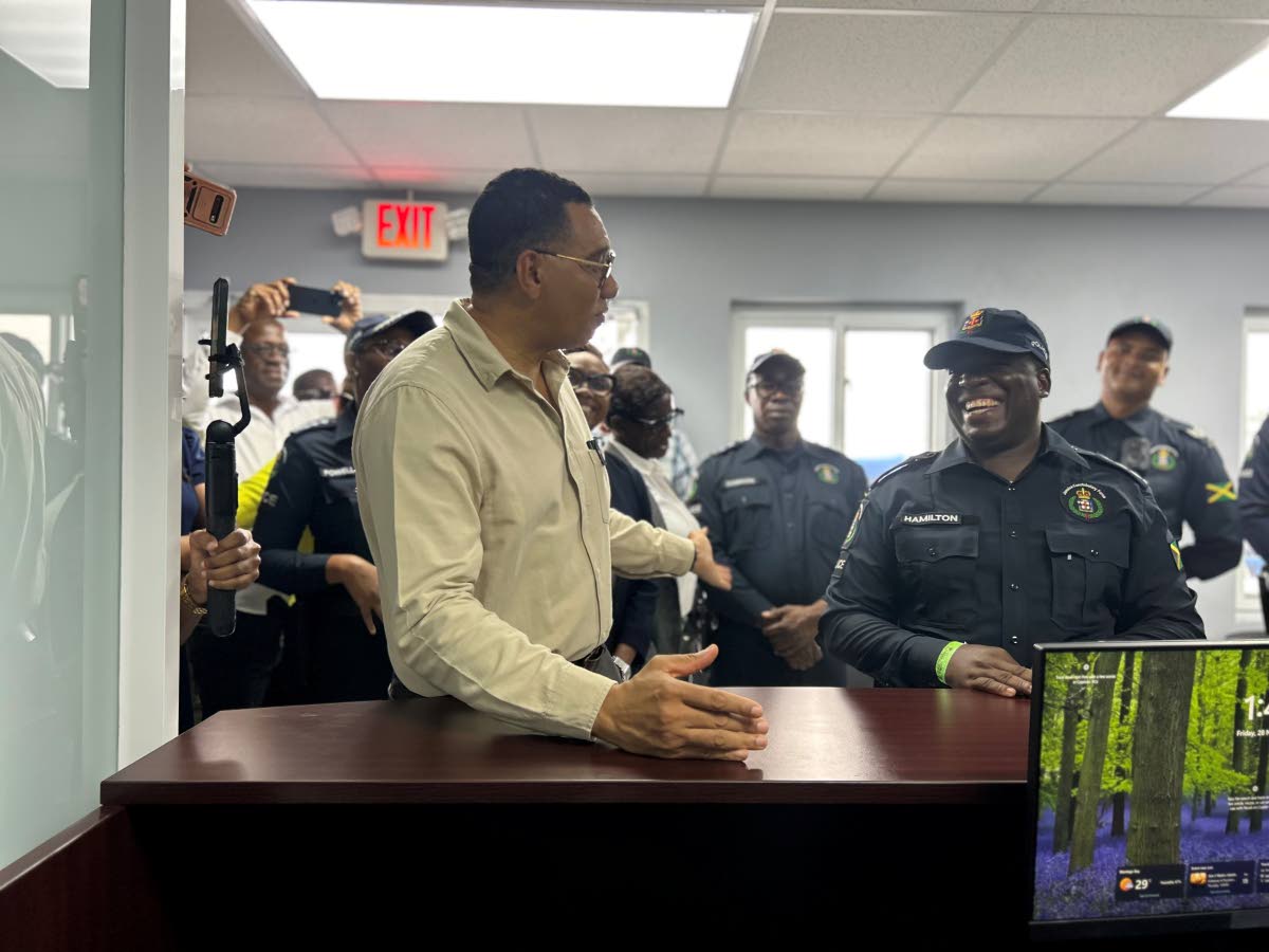 Prime Minister Dr Andrew Holness (left) interacting with Deputy Superintendent Joel Hamilton (right), project manager at the Services Branch, and other cops during a tour of the facilities.