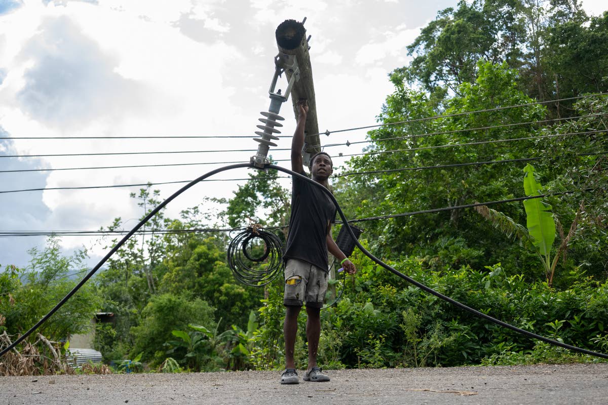 Richard Edwards walks past a downed light pole and dangling wires along the Enfield main road in St Mary.