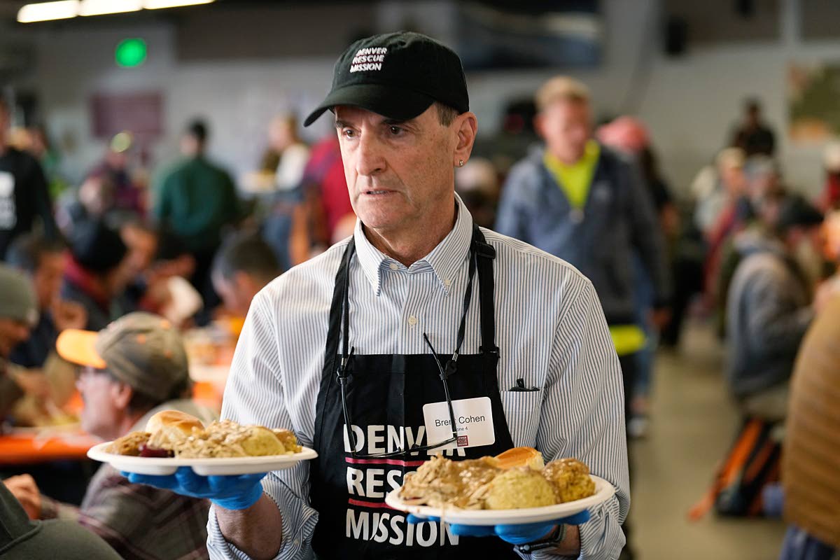 Volunteer Brent Cohen carries plates of food to guests during the annual Thanksgiving banquet at the Denver Rescue Mission on November 22, 2023, in Denver, Colorado.