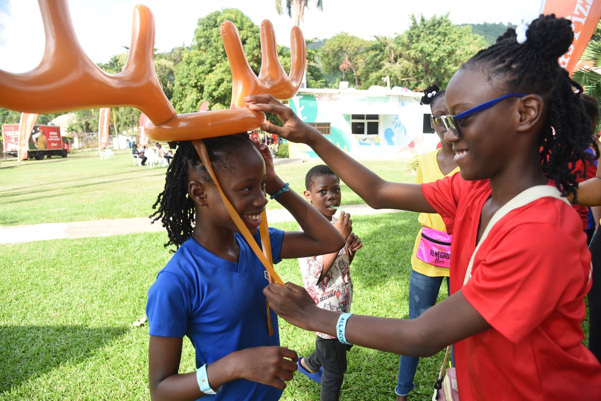 Akeelia Johnson (right) fits antlers to the head of Shakeira Morris (left) during the Digicel Foundation Christmas treat for special needs children at Funland at Hope Gardens on Friday. Both are from the Salvation Army School for the Blind and Visually Imp
