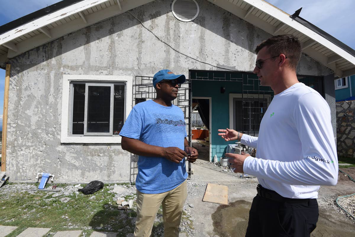 Anthony Davis (left), a homeowner in Edmund Ridge Estates, consults with Landen Craft, senior property adjuster at international adjusting firm Sedgwick, outside his Hurricane Melissa-ravaged home recently.