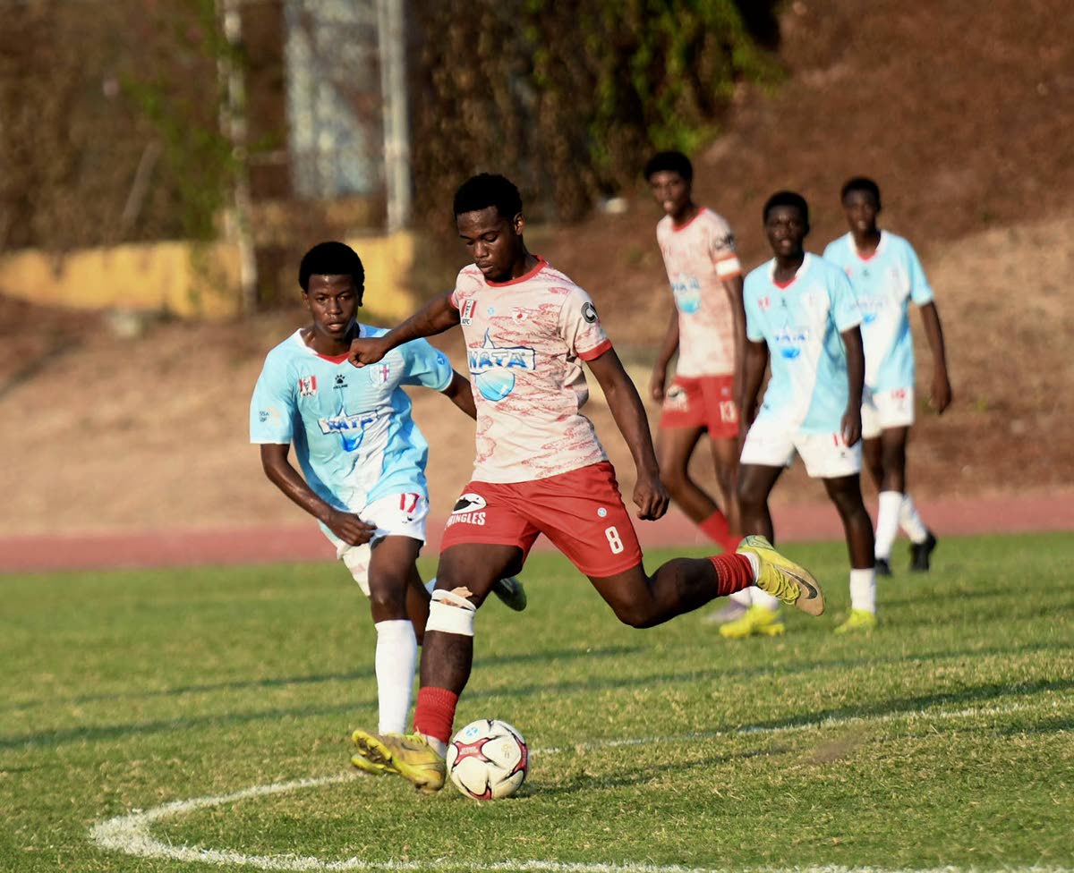 Javade Wallace of Mona High School (second left) looks to kick the ball as Malik Garriques (left) of St George’s College reacts during the Walker Cup KO match at Stadium East yesterday. Mona won the game 4-2.