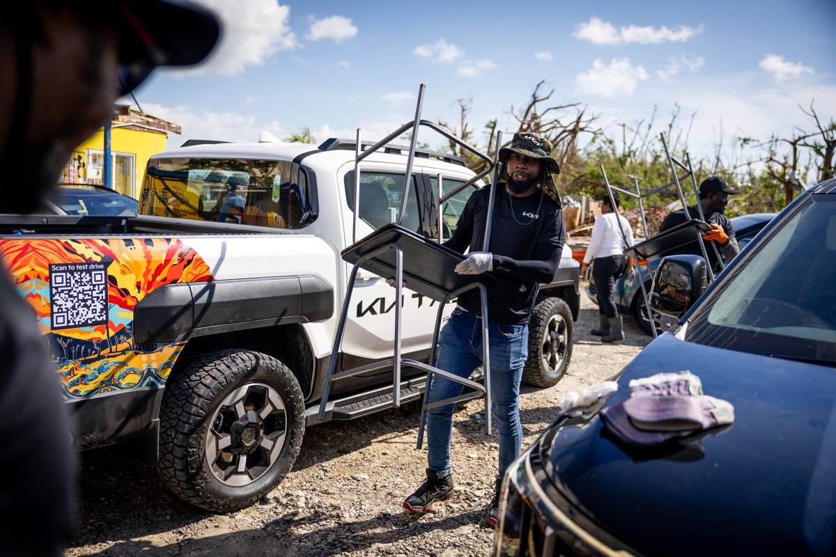Dwayne McKenzie, Senior Sales Supervisor, Kia Jamaica, carries salvaged classroom furniture.
