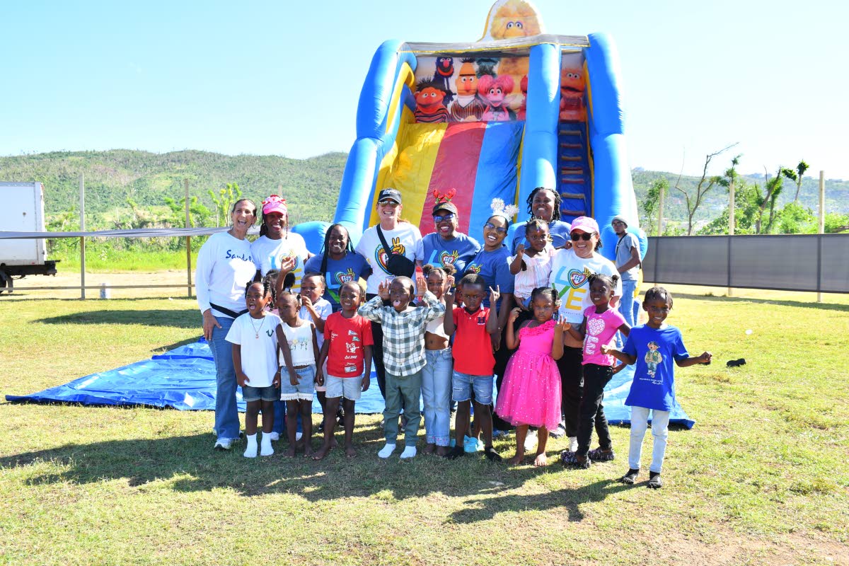 Sandals team members join children in Whitehouse, Westmoreland, for a photo at the Christmas treat on Thursday.