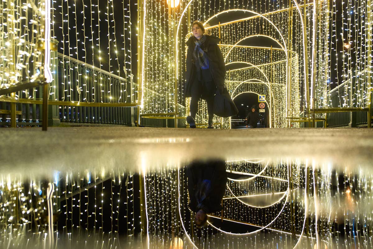 A woman walks across a bridge decorated prior to Christmas and New Year festivities in St Petersburg, Russia, on December 11, 2025.