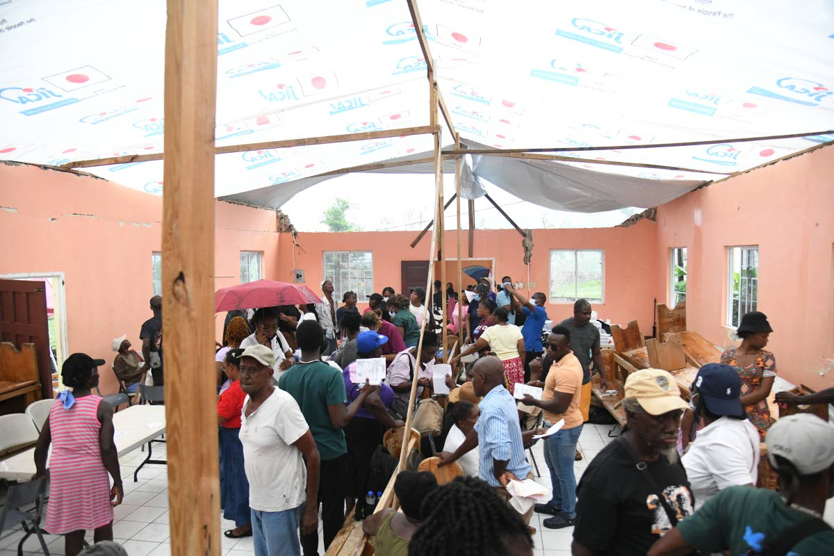 As the rain came pouring in, residents and volunteers unite their efforts to ease the water from piercing through the tarpaulin being used as a makeshift roof on December 13 at the Mother Lewis AME Church in Shrewsbury, Westmoreland. 